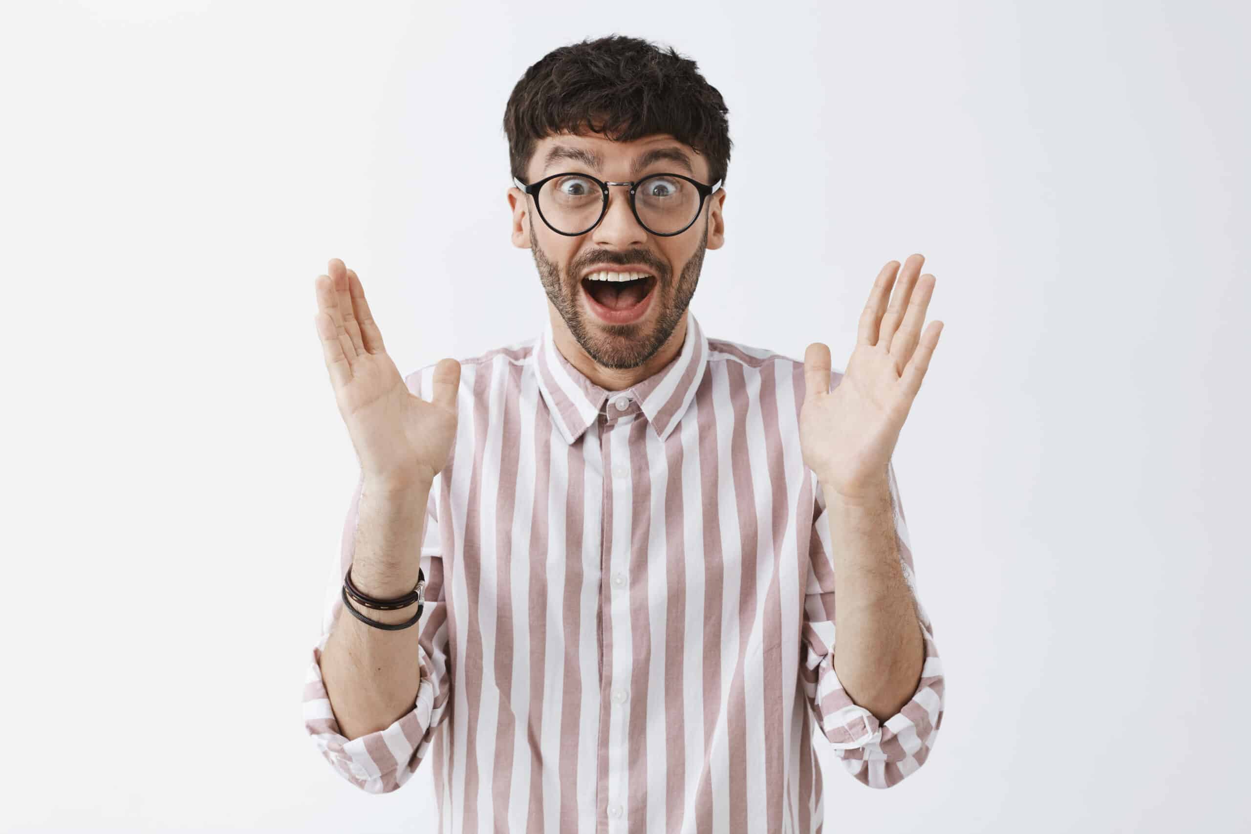 Waist-up shot of enthusiastic excited attractive guy in glasses clapping hands after having great idea or liking lecture smiling broadly with excitement and amazement feeling happy over gray wall.